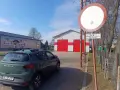 Zielony Dacia Sandero zaparkowany przy remizie OSP. Znak zakazu wjazdu, który może oznaczać mandat za wjazd pod zakaz, jest widoczny obok.