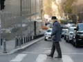 Starszy pan w kapeluszu i maseczce przechodzi przez pasy, unikając potrącenia na ruchliwej ulicy.