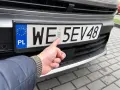 Palec wskazuje hologram na tablicy rejestracyjnej. Uniknij kary za nieprzerejestrowanie pojazdu, dbając o aktualność dokumentów.