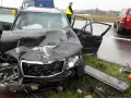 Zniszczony czarny samochód po wypadku, z otwartymi drzwiami i poobijanym przodem. Policjant stoi obok. Zastanawiasz się, ile wzrasta OC po szkodzie?