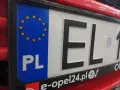 Tablica rejestracyjna samochodu z oznaczeniem PL i gwiazdkami UE. Litery EL i cyfry 1.