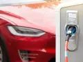 Czerwona Tesla podłączona do ładowarki. Zastanawiasz się, ile ładuje się Tesla? Czas ładowania zależy od modelu i mocy ładowarki.