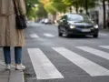 Osoba czeka na chodniku przy pasach. Samochód zbliża się do przejścia, ale czy pieszy zbliżający się do przejścia ma pierwszeństwo?