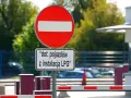 Zakaz wjazdu znak dla pojazdów z instalacją LPG. Barierka i budynek w tle.