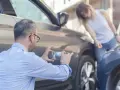 Mężczyzna robi zdjęcie uszkodzeń samochodu, podczas gdy kobieta pochyla się nad pojazdem. To dowód na ucieczkę z miejsca kolizji.