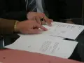 Dwóch mężczyzn analizuje dokumenty, jeden wskazuje palcem na tekst. Może to być wypowiedzenie umowy AC.