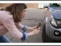 Kobieta robi zdjęcia uszkodzeń samochodu po kolizji, dokumentując szkody do oględzin rzeczoznawcy.