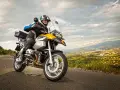 Motocyklista w kasku i kurtce jedzie drogą z widokiem na miasto w oddali. To może być początek jego przygody z rejestracją motocykla z zagranicy.