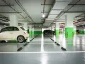 Jasny samochód i ciemny SUV na parkingu podziemnym. Widać odległość miejsca postojowego od ściany, zaznaczoną przez czarne odbojniki.