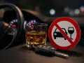 Kary za jazdę po alkoholu są surowe. Na zdjęciu kluczyki do auta, szklanka z whisky i znak zakazu prowadzenia pojazdów po spożyciu alkoholu.