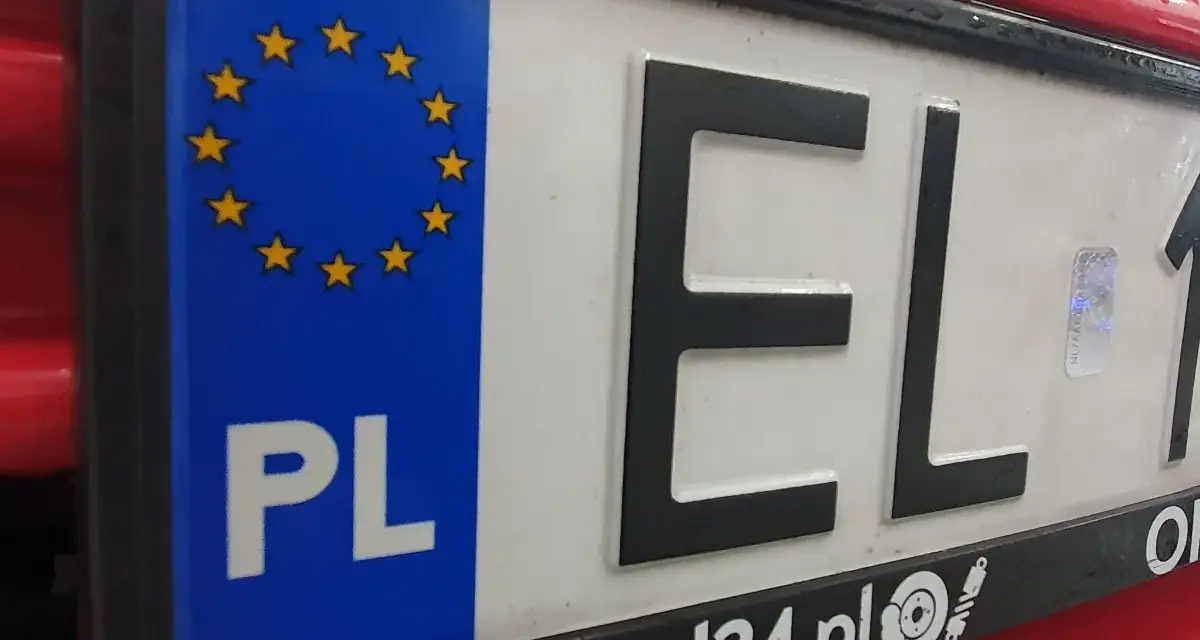 Tablica rejestracyjna samochodu z oznaczeniem PL i gwiazdkami UE. Litery EL i cyfry 1.