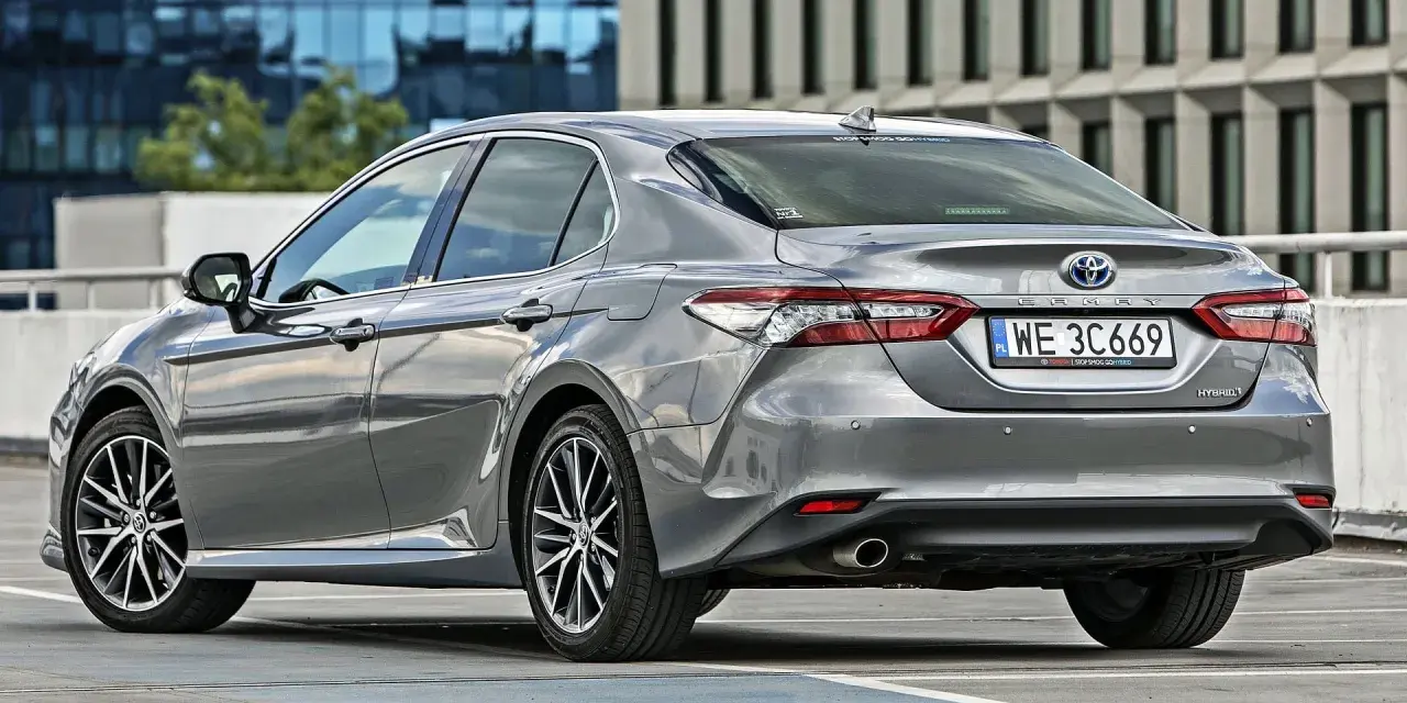 Szary sedan Toyota Camry Hybrid zaparkowany na parkingu. Sprawdź pojemność bagażnika tej hybrydy.