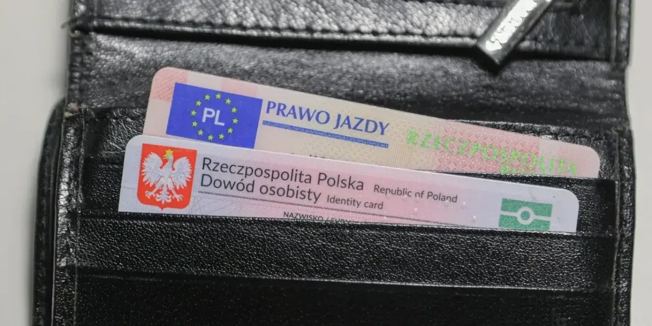 Czarny portfel z polskim dowodem osobistym i prawem jazdy. Widoczne oznaczenia dokumentów.
