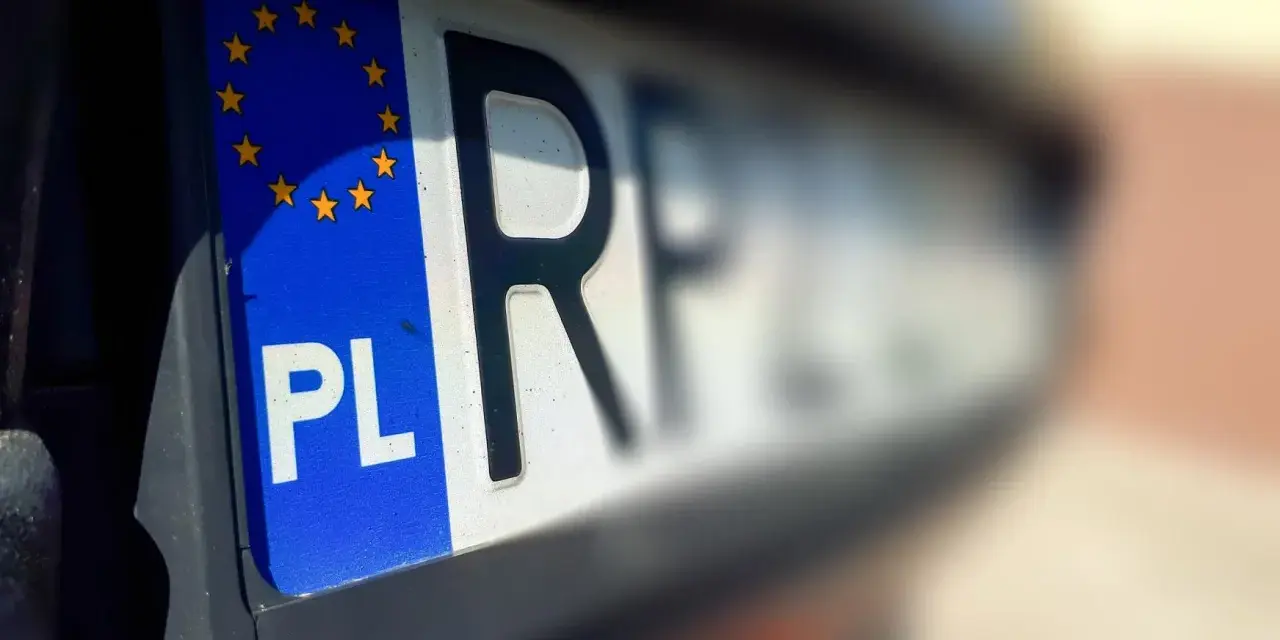 Zbliżenie na polskie rejestracje samochodowe z symbolem Unii Europejskiej. Litery "PL" i część numeru rejestracyjnego są wyraźne.