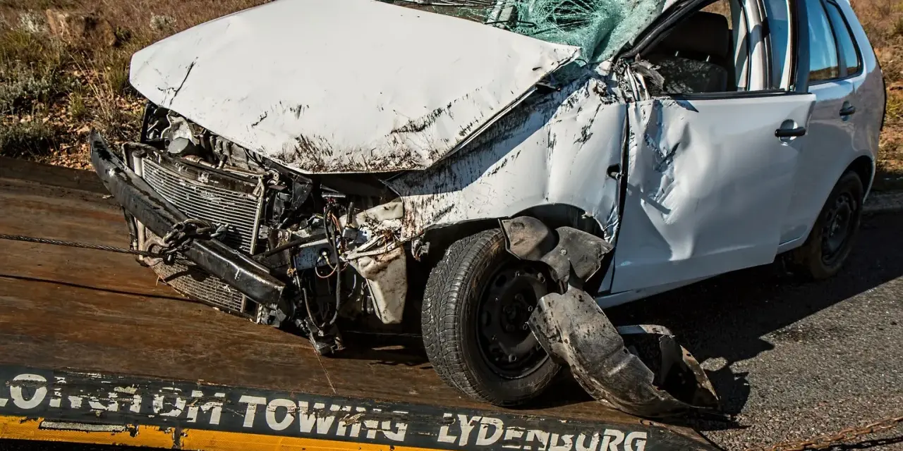 Biały samochód na lawecie z widocznymi uszkodzeniami, pęknięta przednia szyba. Wygląda na to, że to szkoda całkowita z OC sprawcy.