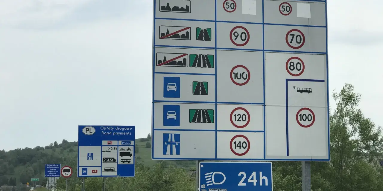 Znaki drogowe informują o opłatach i limitach prędkości na drodze ekspresowej. Maksymalna dozwolona prędkość dla samochodów osobowych to 140 km/h.