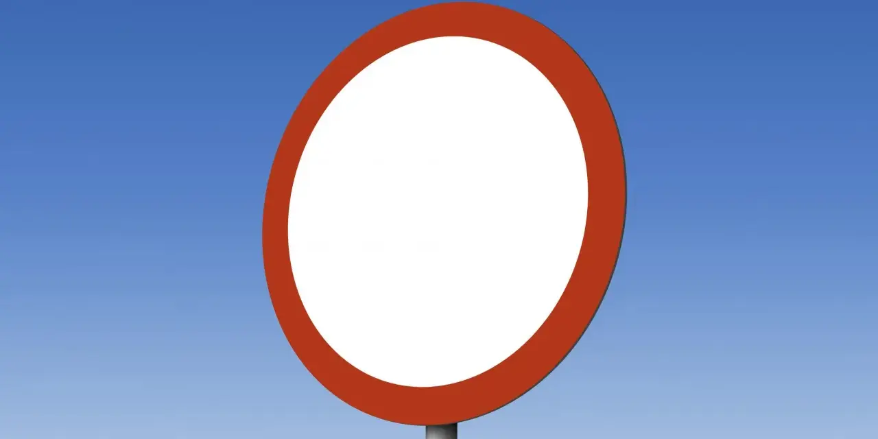 Okrągły, biały znak drogowy b1 z czerwoną obwódką na tle błękitnego nieba.
