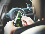 Ręce otwierają butelkę piwa za kierownicą. To niebezpieczna jazda pod wpływem alkoholu, która może skończyć się tragicznie.