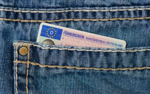 Niebieskie jeansy z kieszenią, w której widać fragment niemieckiego prawa jazdy. Brak karty pojazdu.