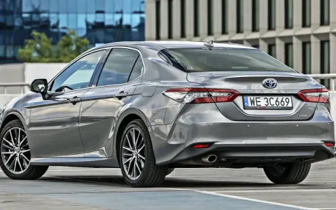 Szary sedan Toyota Camry Hybrid zaparkowany na parkingu. Sprawdź pojemność bagażnika tej hybrydy.