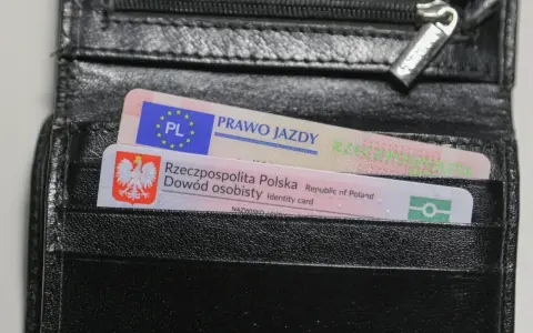 Czarny portfel z polskim dowodem osobistym i prawem jazdy. Widoczne oznaczenia dokumentów.