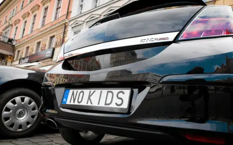 Czarne auto z indywidualnymi tablicami rejestracyjnymi "NO KIDS". Przykłady takich tablic pokazują kreatywność kierowców.