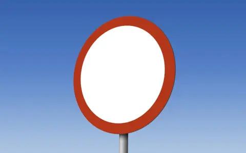 Okrągły, biały znak drogowy b1 z czerwoną obwódką na tle błękitnego nieba.