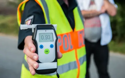 Policjant w kamizelce odblaskowej pokazuje alkomat z wynikiem 0.93 promila. Rutynowa kontrola trzeźwości na drodze.