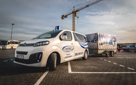 Biały bus z literą "L" na dachu i przyczepa z napisem "Classic" i "KAT. B+E". Nauka jazdy daje nowe możliwości.