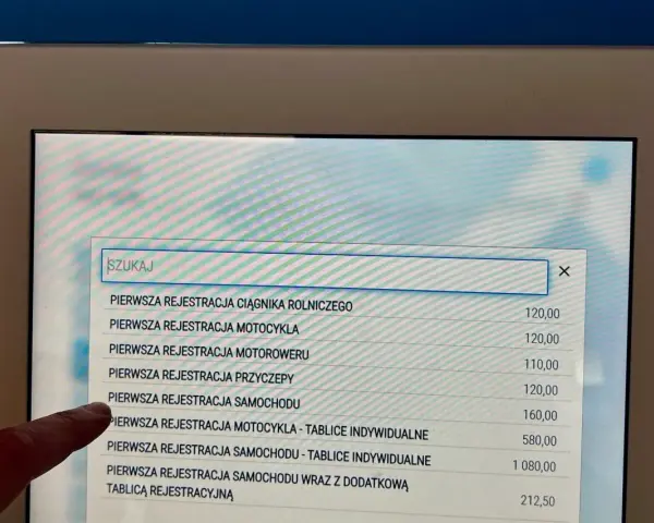 Palec wskazuje opcję "PIERWSZA REJESTRACJA SAMOCHODU" na ekranie, gdzie szukamy informacji, jak napisać upoważnienie do wyrejestrowania samochodu.