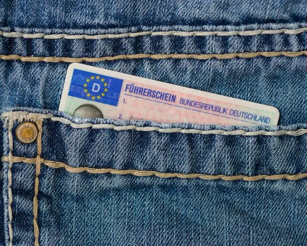 Niebieskie jeansy z kieszenią, w której widać fragment niemieckiego prawa jazdy. Brak karty pojazdu.