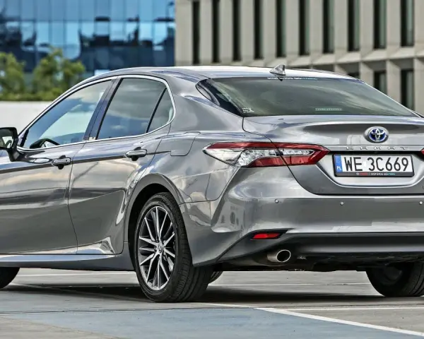 Szary sedan Toyota Camry Hybrid zaparkowany na parkingu. Sprawdź pojemność bagażnika tej hybrydy.