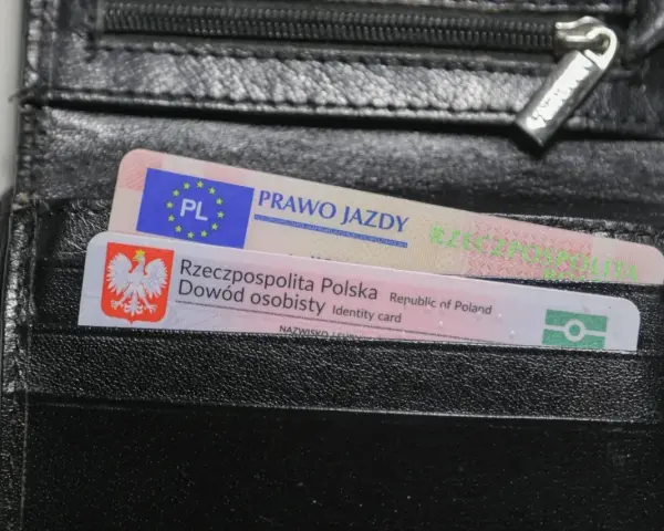 Czarny portfel z polskim dowodem osobistym i prawem jazdy. Widoczne oznaczenia dokumentów.
