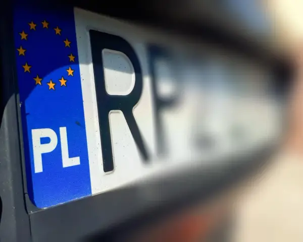 Zbliżenie na polskie rejestracje samochodowe z symbolem Unii Europejskiej. Litery "PL" i część numeru rejestracyjnego są wyraźne.