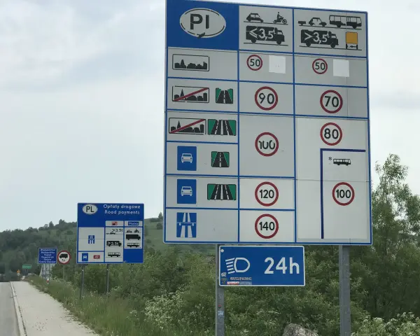 Znaki drogowe informują o opłatach i limitach prędkości na drodze ekspresowej. Maksymalna dozwolona prędkość dla samochodów osobowych to 140 km/h.