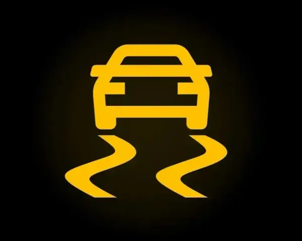 Żółty symbol ESP na czarnym tle. Auto jedzie po śliskiej drodze, co oznacza, że system kontroli trakcji jest aktywny.