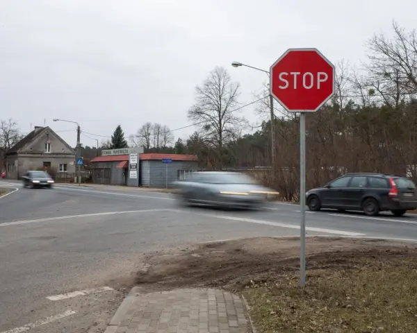 Znak STOP i linia warunkowego zatrzymania na skrzyżowaniu. Samochody w ruchu.