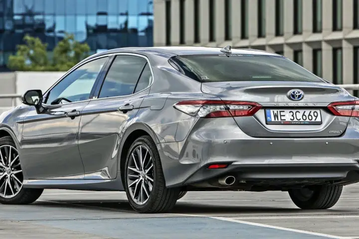Szary sedan Toyota Camry Hybrid zaparkowany na parkingu. Sprawdź pojemność bagażnika tej hybrydy.