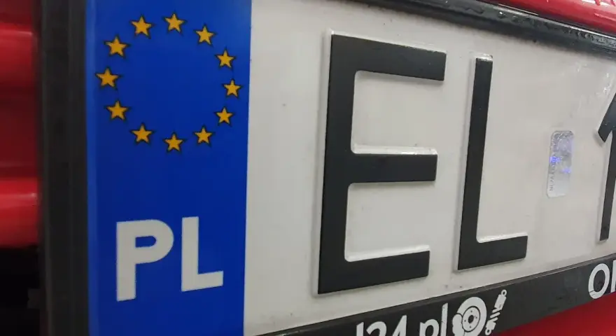 Tablica rejestracyjna samochodu z oznaczeniem PL i gwiazdkami UE. Litery EL i cyfry 1.