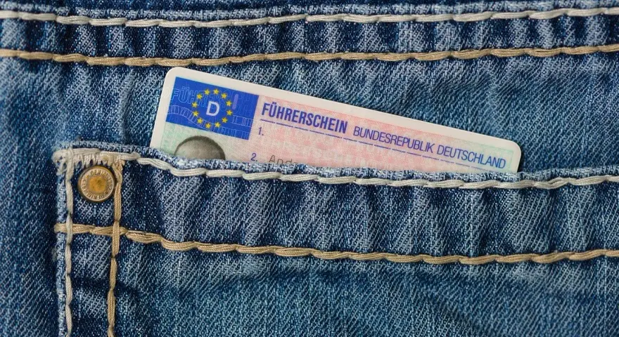 Niebieskie jeansy z kieszenią, w której widać fragment niemieckiego prawa jazdy. Brak karty pojazdu.
