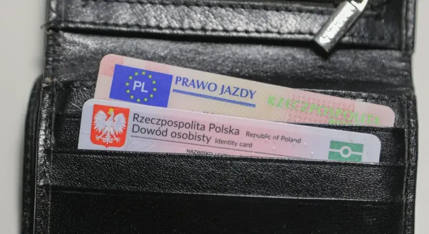 Czarny portfel z polskim dowodem osobistym i prawem jazdy. Widoczne oznaczenia dokumentów.