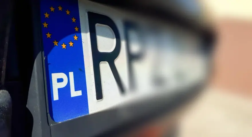 Zbliżenie na polskie rejestracje samochodowe z symbolem Unii Europejskiej. Litery "PL" i część numeru rejestracyjnego są wyraźne.