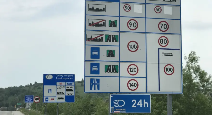 Znaki drogowe informują o opłatach i limitach prędkości na drodze ekspresowej. Maksymalna dozwolona prędkość dla samochodów osobowych to 140 km/h.