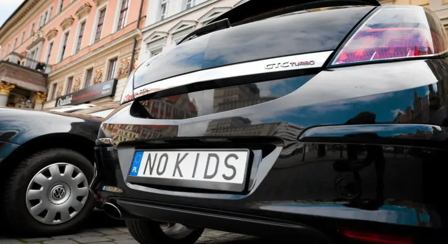 Czarne auto z indywidualnymi tablicami rejestracyjnymi "NO KIDS". Przykłady takich tablic pokazują kreatywność kierowców.