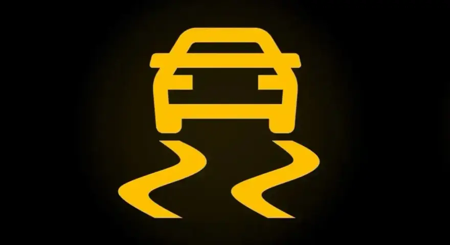 Żółty symbol ESP na czarnym tle. Auto jedzie po śliskiej drodze, co oznacza, że system kontroli trakcji jest aktywny.