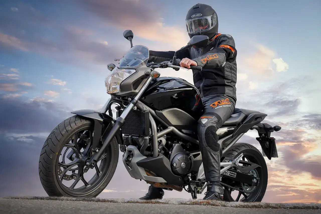 Czarny motocykl Honda NC700S, idealny na kategorię B prawa jazdy. Kierowca w kombinezonie i kasku.