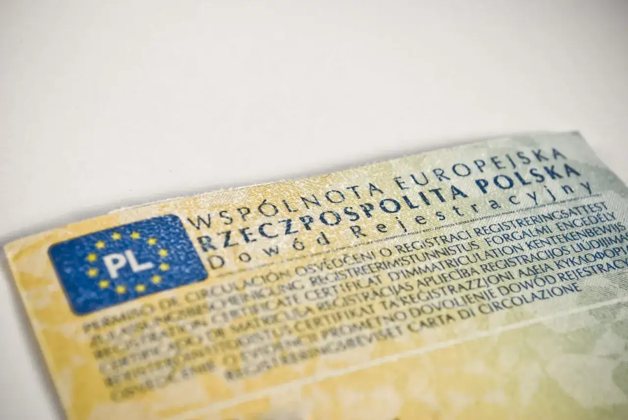 Dowód rejestracyjny z flagą PL. Dokument zawiera tekst w wielu językach, w tym polski
