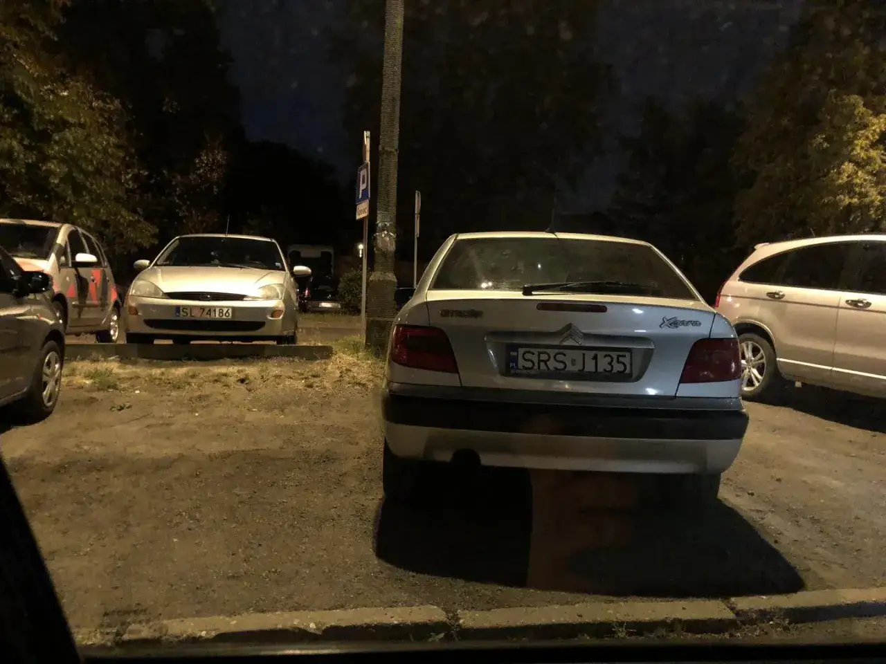 Samochód z rejestracją SL 74186 i Citroën z tablicą SRS J135 stoją na parkingu nocą.