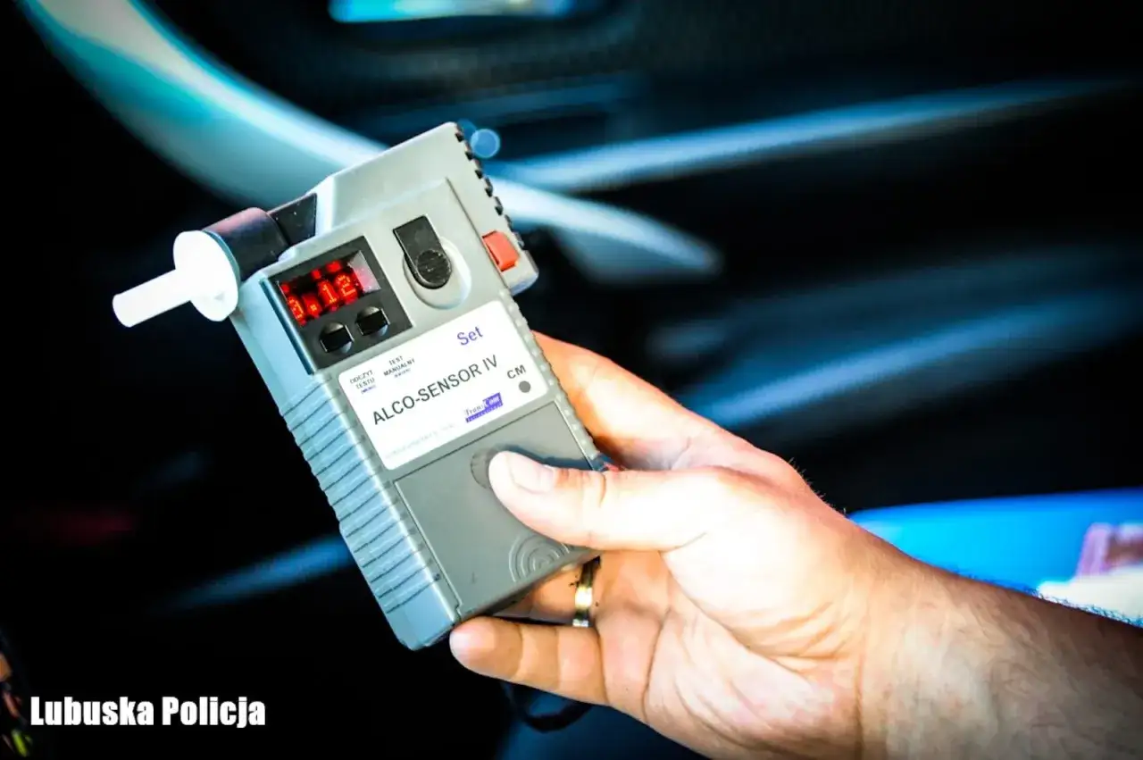 Dłoń trzyma alkomat z wynikiem 0.12. Policja przypomina o limicie alkoholu w Polsce.