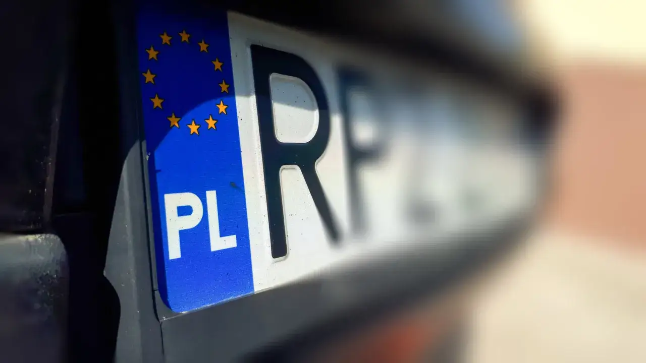 Zbliżenie na polską tablicę rejestracyjną z symbolem UE. Zastanawiasz się, ile kosztują tablice rejestracyjne?